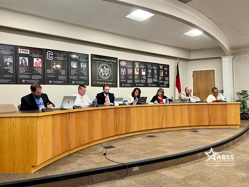 Photo of Board of Education in session with BOE sitting at desk. 