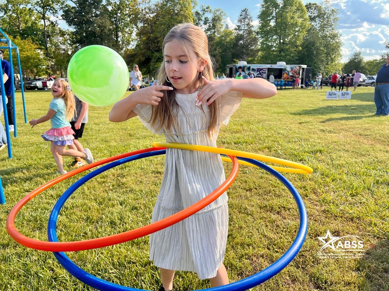 Girl with 3 hoops around waist with children in background